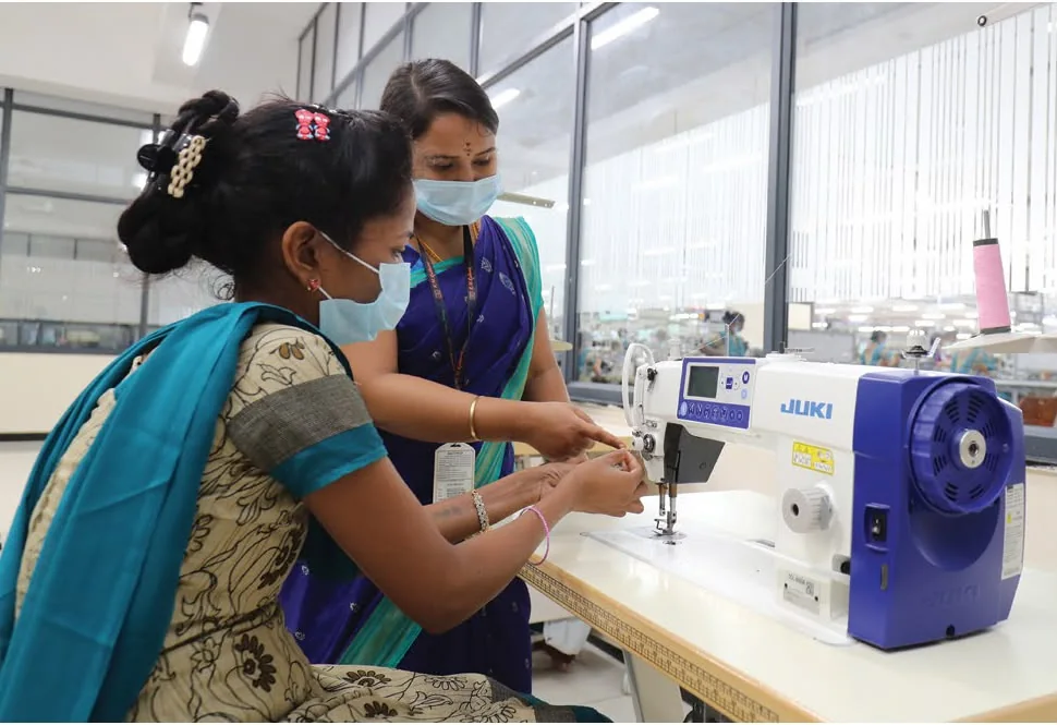 Two garment workers training at an industrial sewing machine